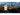 Nitecore NWE10 electronic outdoor whistle shown in a promotional graphic over a mountain landscape. The white whistle with an orange button is displayed alongside orange sound wave icons, with text reading 'Electronic Outdoor Whistle 4 x Sound Intensity' and 'NITECORE NWE10 123 dB'.