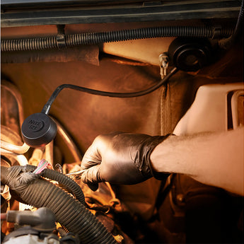 Person wearing gloves working on a car engine with a close-up of the Nite Ize Flex Lamp