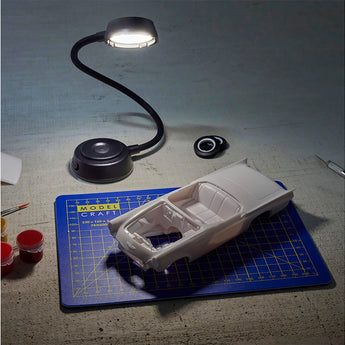 Model car kit on a cutting mat with a small lamp illuminating it